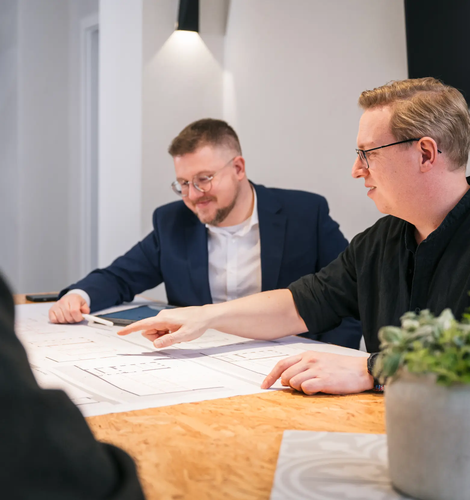 Richard Gunkel und sein Kollege besprechen Architekturpläne am gemeinsamen Tisch