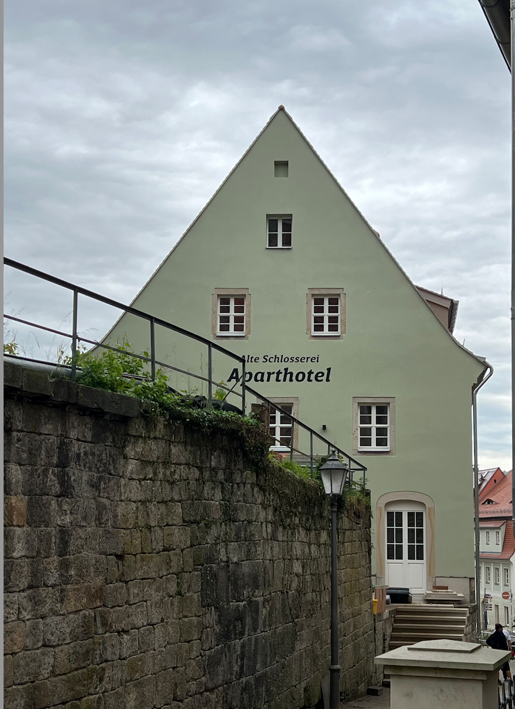 Alte Schlosserei Königstein: Blick auf die Giebelfassade hinter der historischen Sandsteinmauer